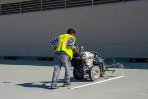 worker using parking lot striping equipment